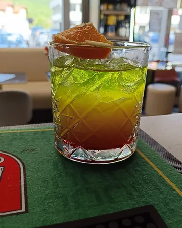 Cocktail a strati verde e rosso con una fetta d'arancia