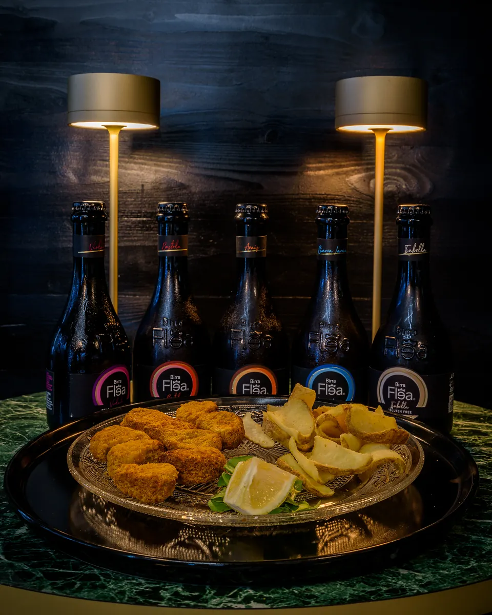 Bottiglie di birra dietro un piatto di fritto con patatine e limone